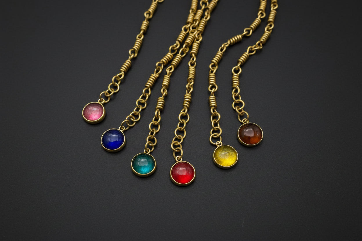Gold bracelets with colorful gemstone pendants on black background