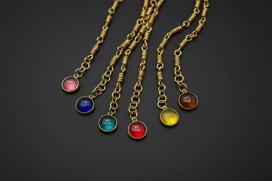 Gold bracelets with colorful gemstone pendants on black background