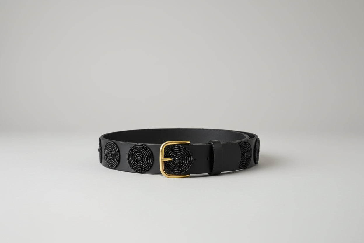 Black leather belt with gold buckle on a light gray background