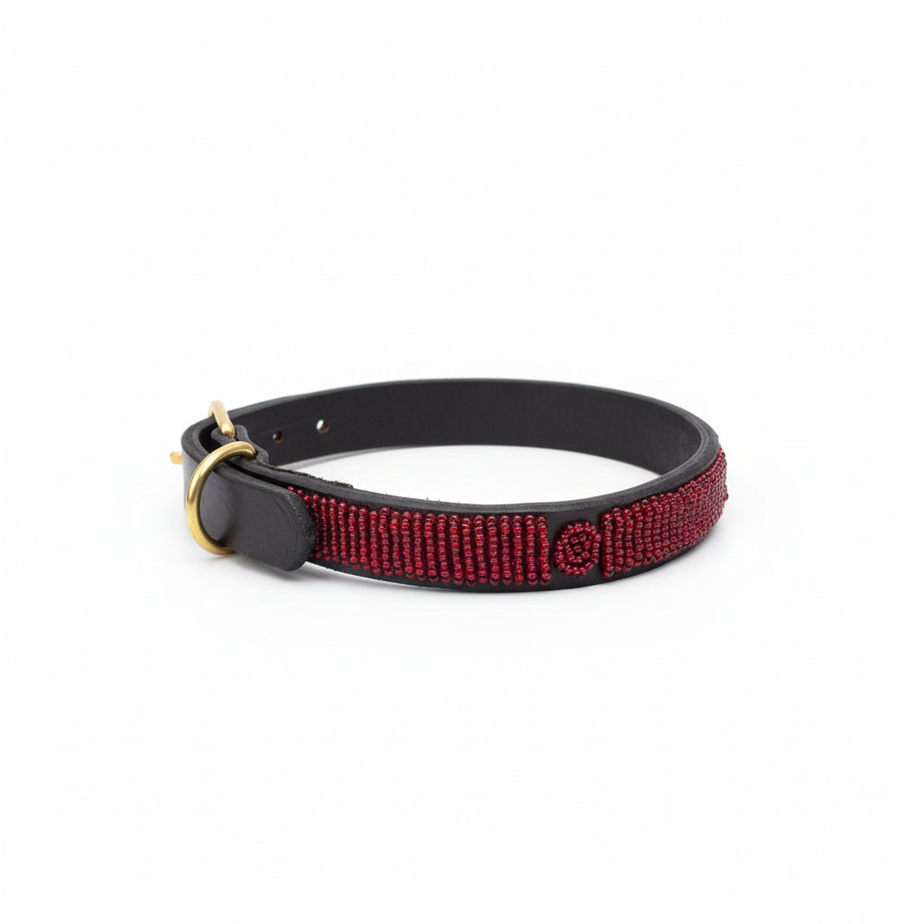 Red beaded dog collar on a beige surface with a blurred indoor background