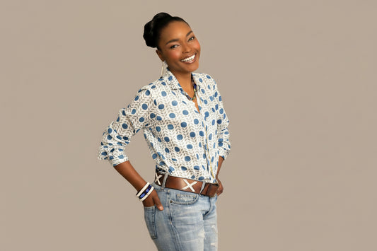 Woman wearing a patterned shirt and jeans on a beige background