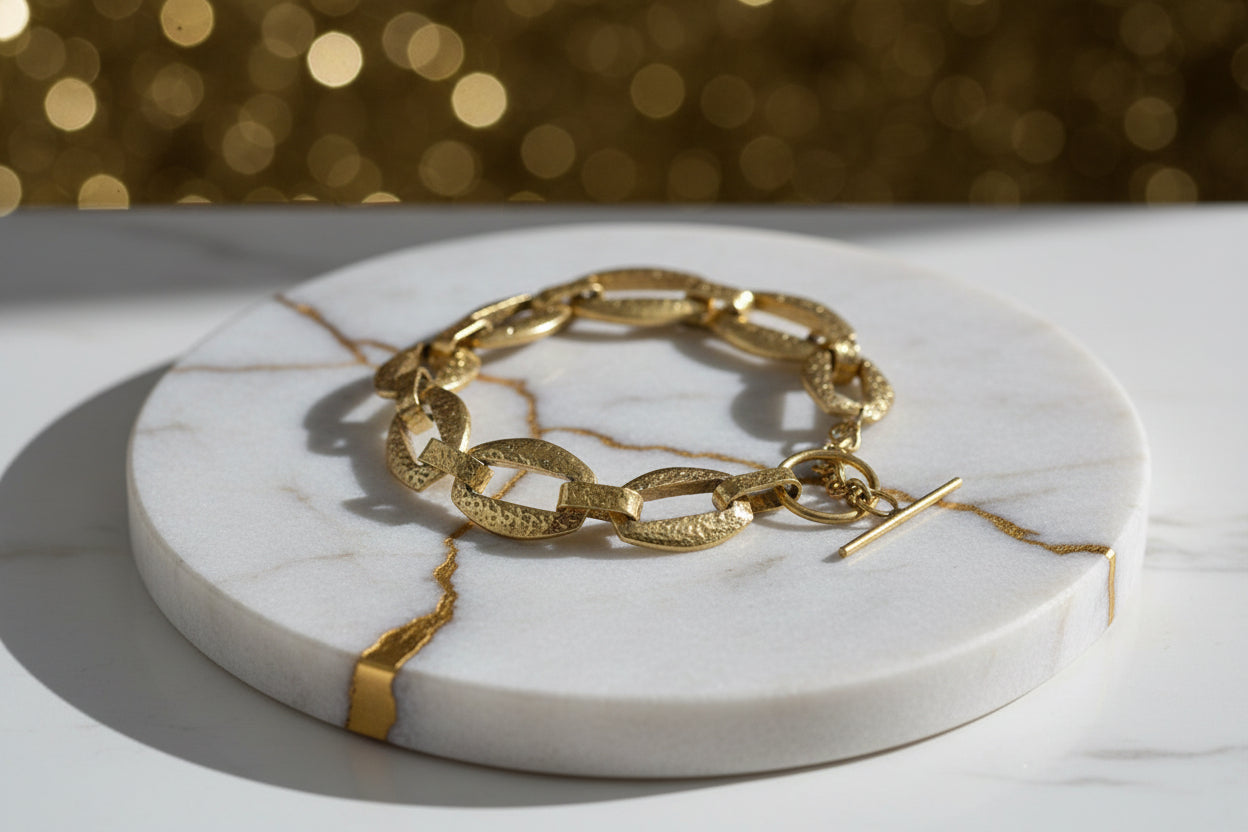 Gold chain bracelet on a marble coaster with a blurred gold background