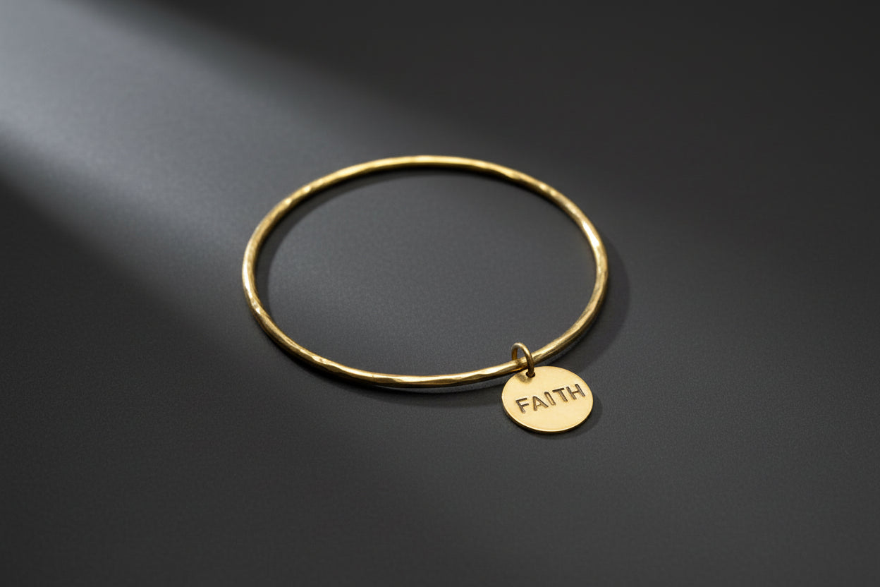 Gold bracelet with a 'FAITH' tag on a dark background