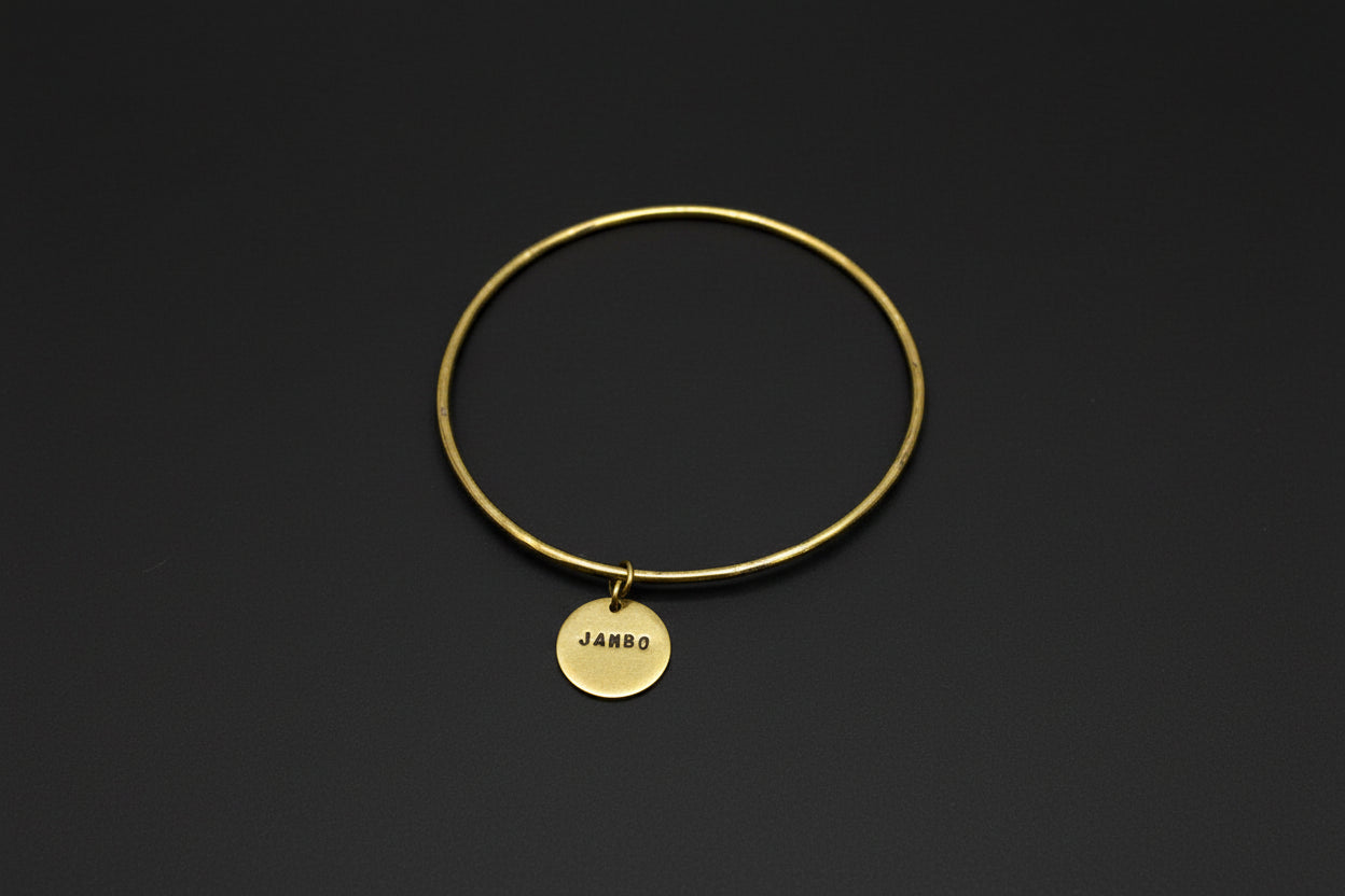 Gold bracelet with a round tag on a black background