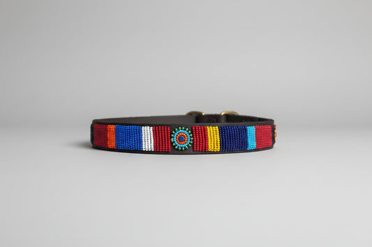 Colorful beaded dog collar on a beige surface with a blurred indoor background