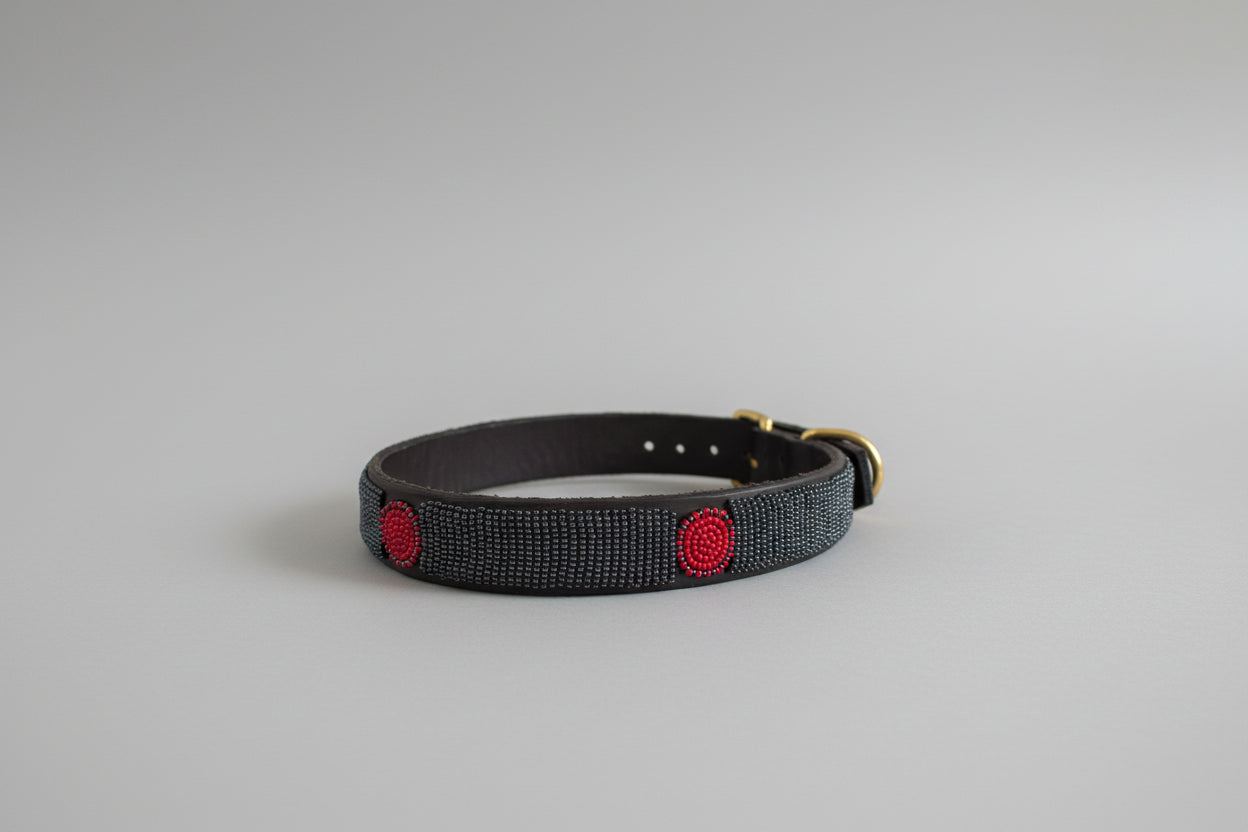 Pewter beaded collar with red accents on a white fabric background