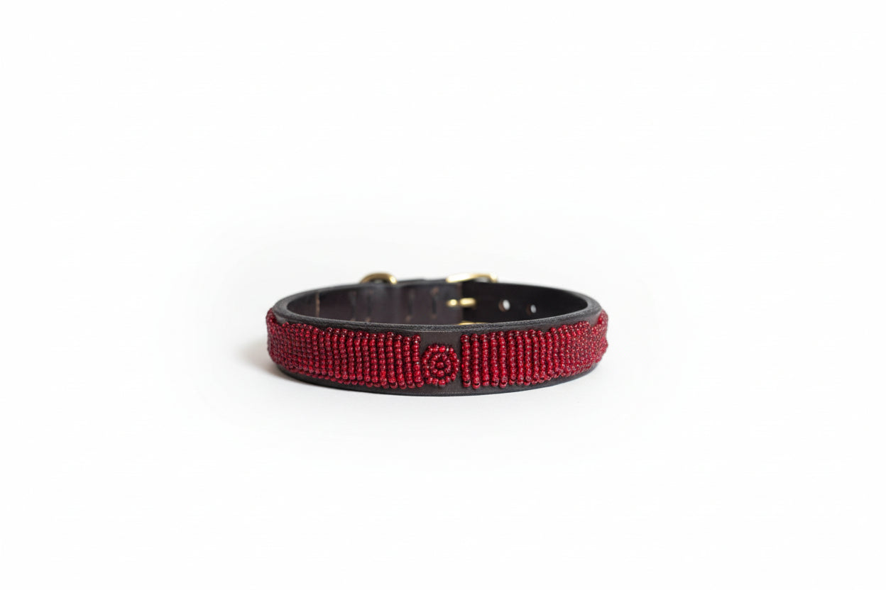 Red beaded dog collar on a beige surface with a blurred indoor background