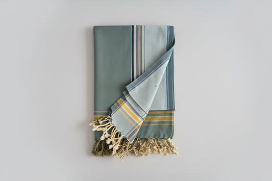 Folded fabric with tassels on a light grey background
