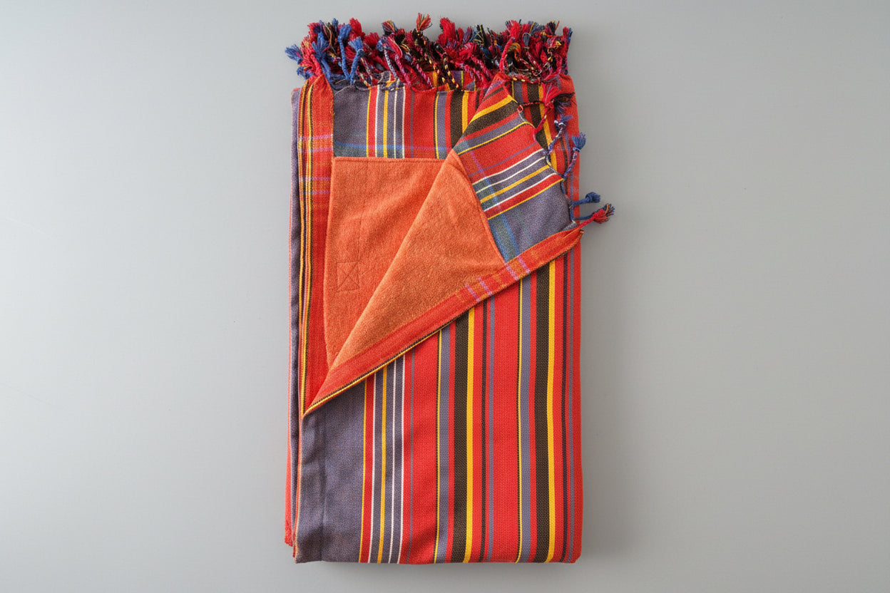 Folded fabric with colorful stripes and tassels on a grey background