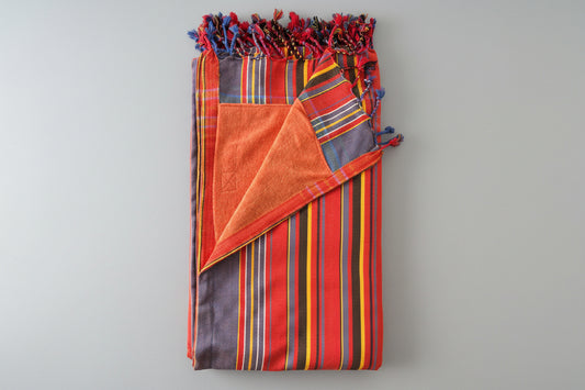 Folded fabric with colorful stripes and tassels on a grey background