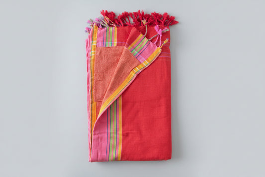 Orange Pink fabric with colourful tassels on a grey background