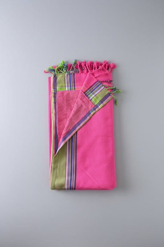 Pink fabric with colourful patterns and tassels on a grey background