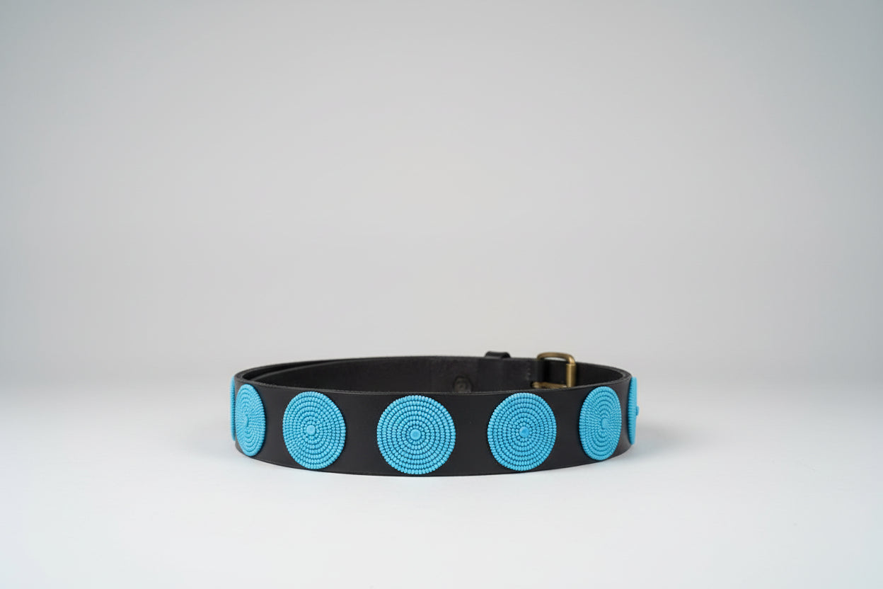 Leather belt with turquoise circular pattern on a grey background