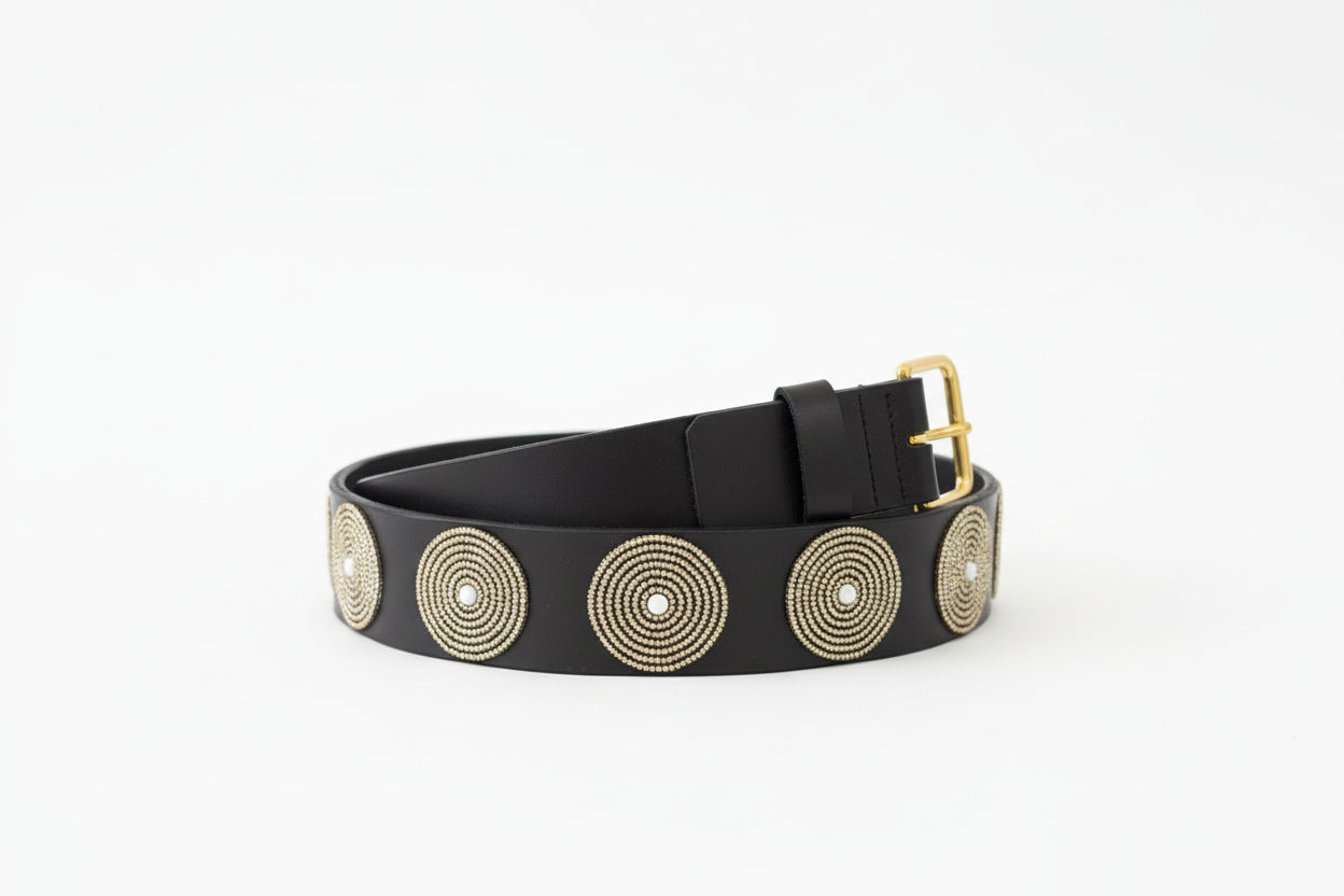 Black belt with gold circular embellishments on a dark surface