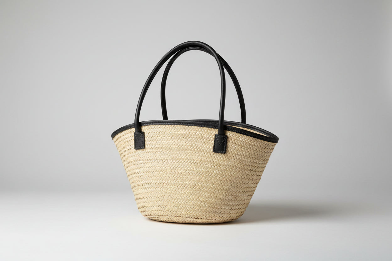 Woven basket with black handles on a striped surface